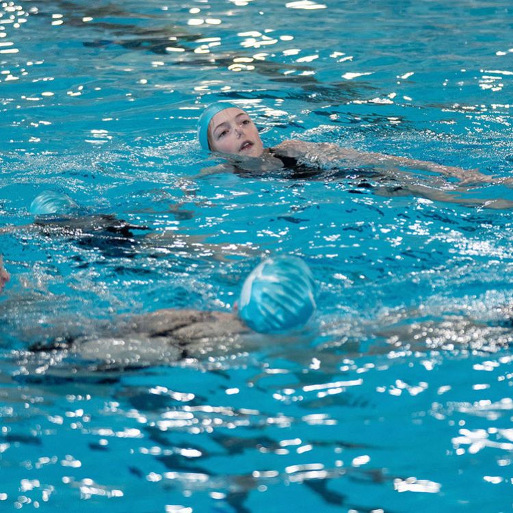 Artistic swimmer girls in pool with legs held high